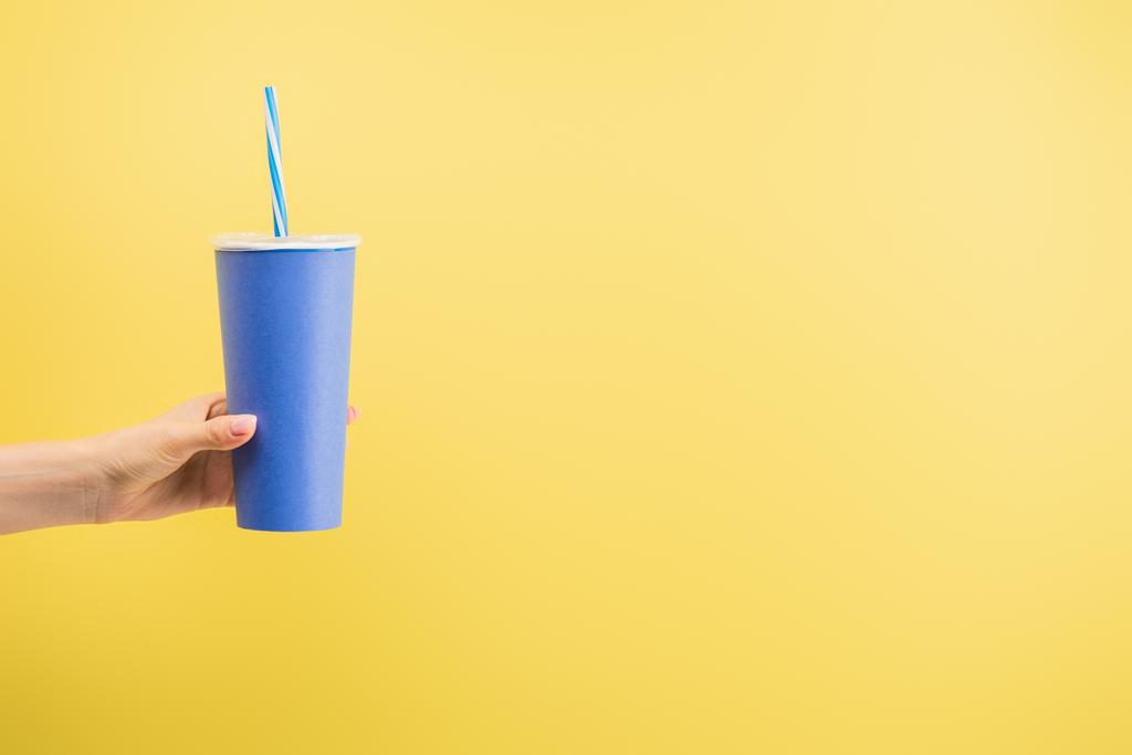 vue recadrée d'une femme tenant une tasse de soda isolée sur du jaune, concept de cinéma - Photo, image