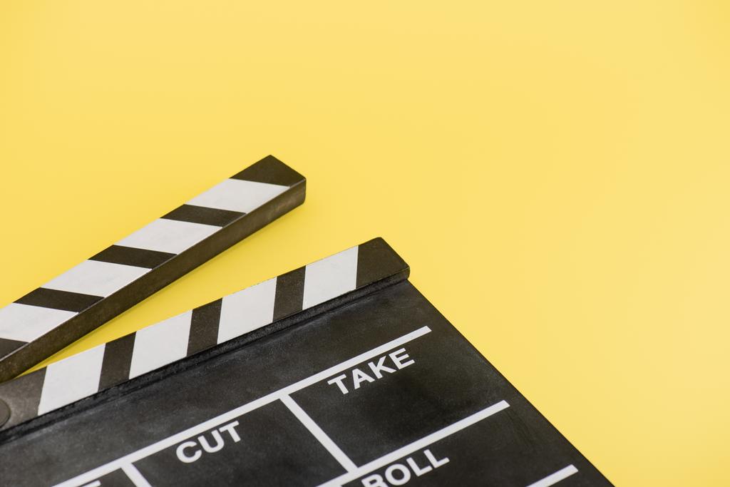黄色を背景にしたクラッパーボードの近景や映画のコンセプト - 写真・画像