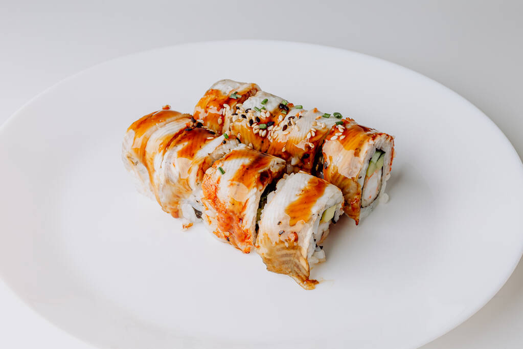 Японская кухня: набор суши маки и нигири. Суши-роллы (Филадельфия) с рисом, рыбным лососем, копченым угрем, авокадо, сливочным сыром, соевым соусом Терияки, кунжутом. Палочки, васаби и маринованная имбирь. - Фото, изображение