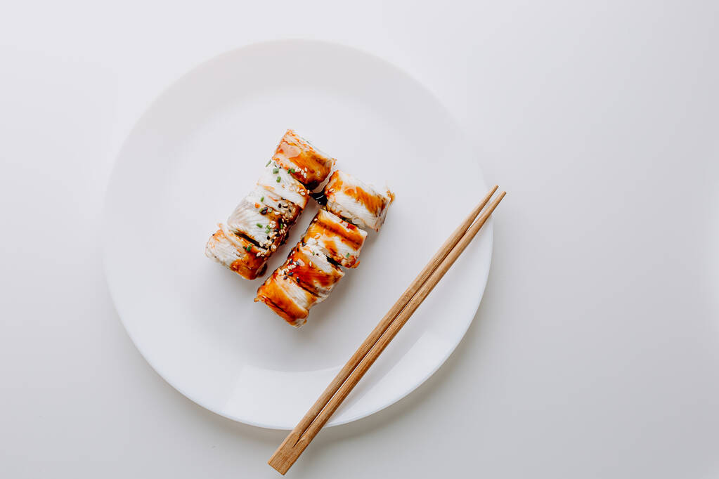 日本料理：巻き寿司と握り寿司セット。寿司ロール(フィラデルフィア)ご飯、魚サーモン、燻製ウナギ、アボカド、クリームチーズ、醤油照り焼きソース、ゴマ。箸、わさび、すりおろした生姜. - 写真・画像