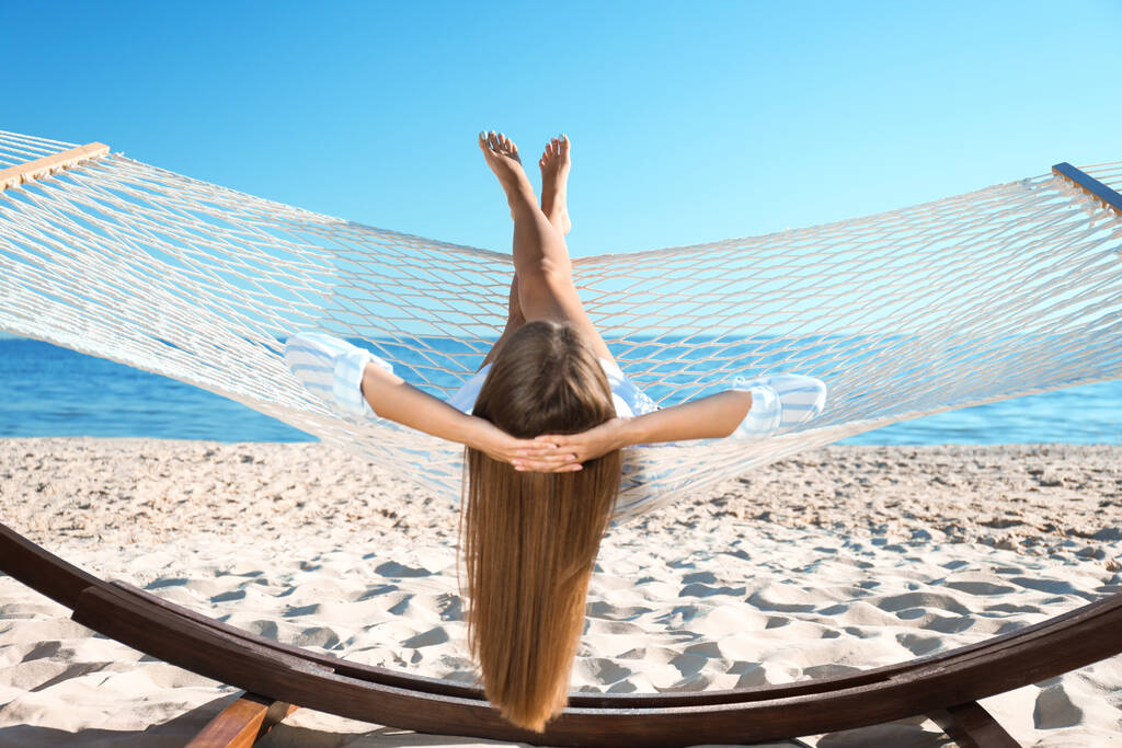 Mujer joven relajándose en hamaca en la playa - Foto, imagen