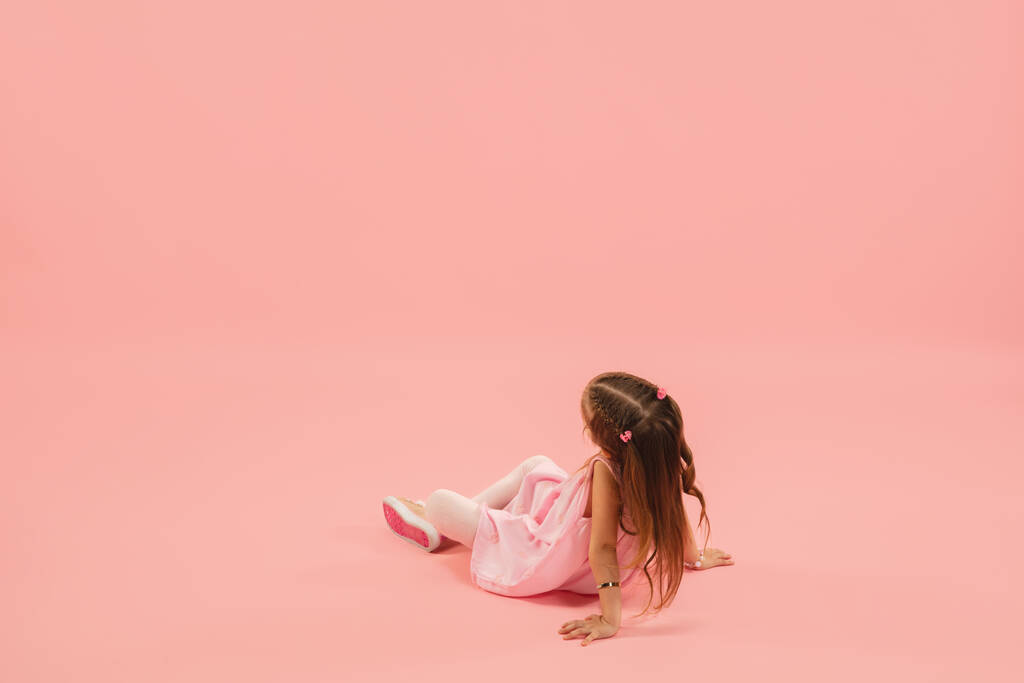 Детство и мечта о большом и знаменитом будущем. Красивая девушка длинные волосы изолированы на коралловом розовом фоне - Фото, изображение