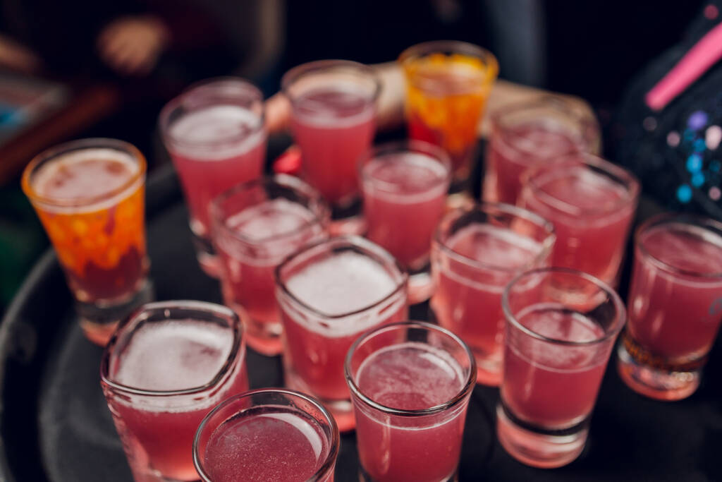 Variation of hard alcoholic shots served on bar counter. Blur bottles on background. - Photo, Image