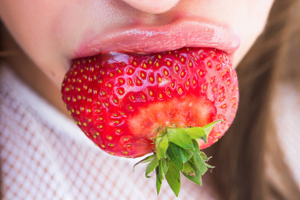 Erdbeere im Mund mit sexy rosigen Lippen. Schönheit, Lippenstift, Lipgloss, Make-up. Sommerfrucht. - Foto, Bild