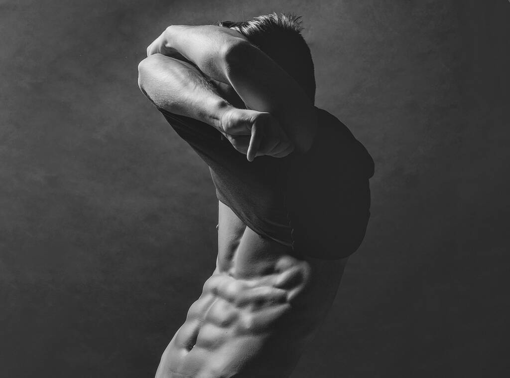 Чувственный сексуальный молодой вдумчивый мужчина в рубашке, раздевающийся голым мускулистым туловищем и надуманным телом. - Фото, изображение