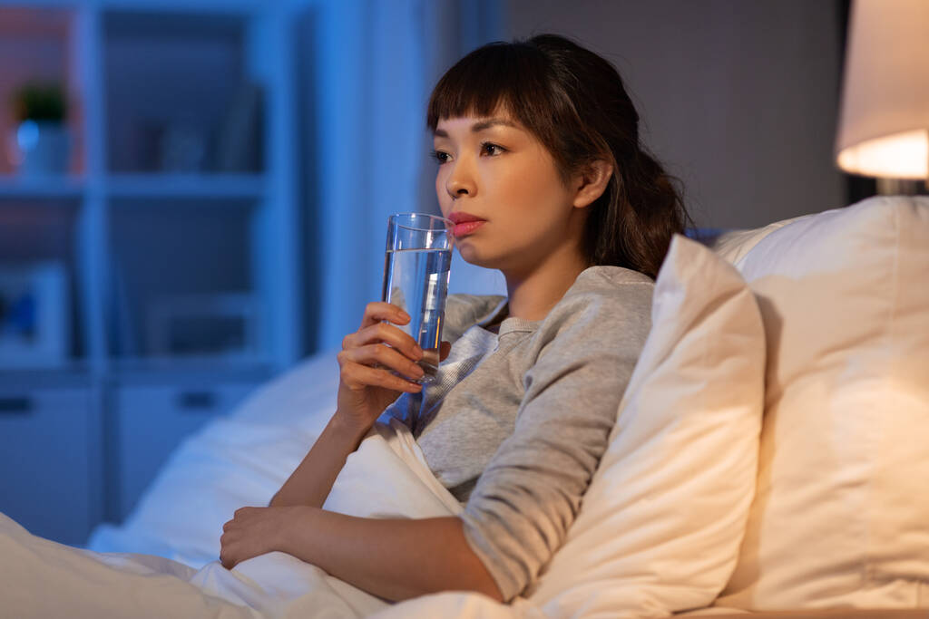 asiática mulher bebendo água à noite na cama - Foto, Imagem