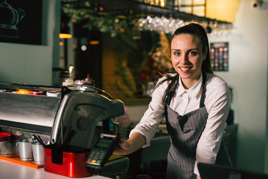 σερβιτόρα που κρατά τερματικό σταθμό, στέκεται στο καφέ - Φωτογραφία, εικόνα