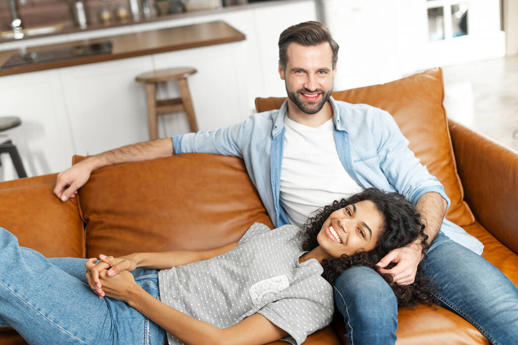 Многорасовая влюбленная пара на диване - Фото, изображение