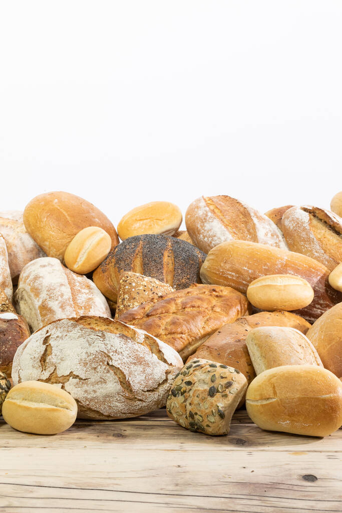 Muchos tipos y tipos de pan recogidos en un solo lugar en un mostrador de madera antigua tienda como decoración para una panadería tradicional. Fondo blanco desde la parte superior para la autocompleción. - Foto, Imagen
