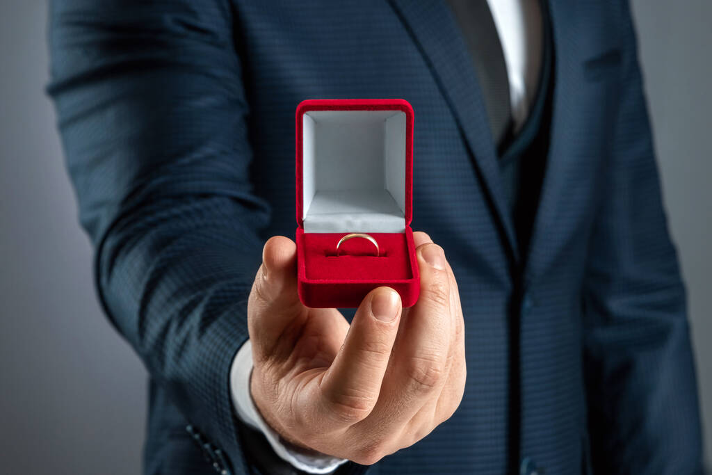 Vezmeš si mě, muž v obleku drží v ruce červenou krabici se snubním prstenem. Pojem sňatek, sňatek, sňatek. Detailní záběr - Fotografie, Obrázek