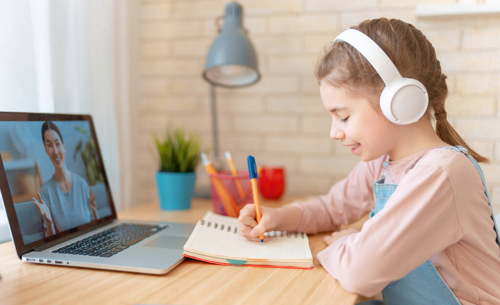 Wracać do szkoły. Szczęśliwe dziecko siedzi przy biurku. Dziewczyna robi pracę domową lub edukację online. - Zdjęcie, obraz