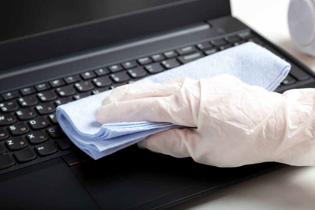 Female hands in gloves disinfecting laptop keyboard using wet disinfectant wipes. Woman cleaning keyboard from viruses bacteria prevent covid coronavirus. New Normal cleaning laptop work home surfaces - Photo, Image