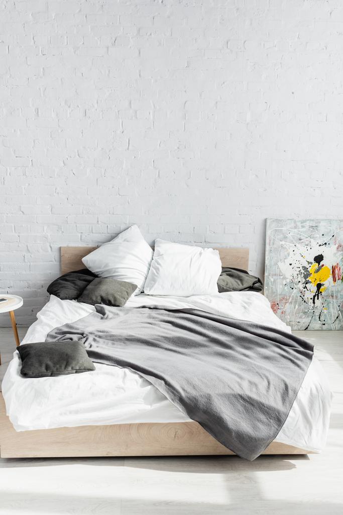Γκρι κουβέρτα και μαξιλάρια στο κρεβάτι στο σπίτι  - Φωτογραφία, εικόνα