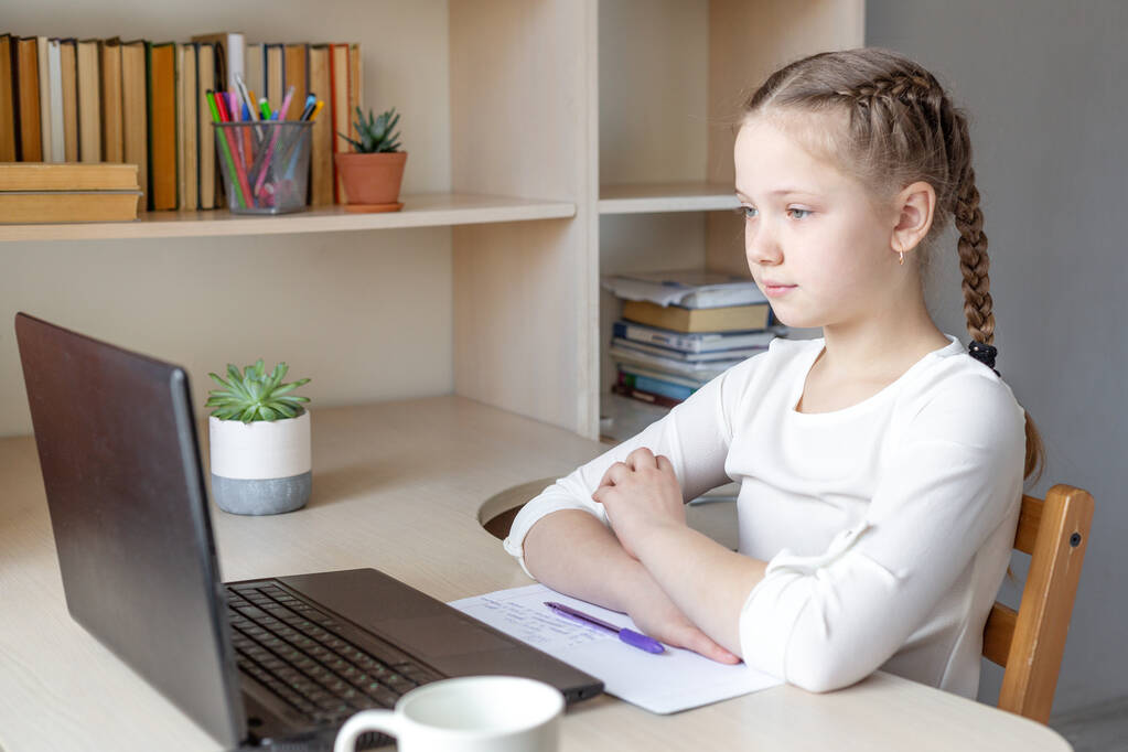 Ciddi bir liseli kız dizüstü bilgisayar ekranına bakıyor. Uzaklık öğrenimi çevrimiçi eğitim, ev okulu, ev eğitimi - Fotoğraf, Görsel