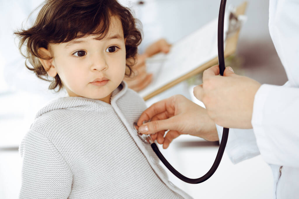 Vrouwendokter die een kindpatiënt onderzoekt met stethoscoop. Leuke Arabische peuter op afspraak bij de dokter. Geneesmiddelenconcept - Foto, afbeelding