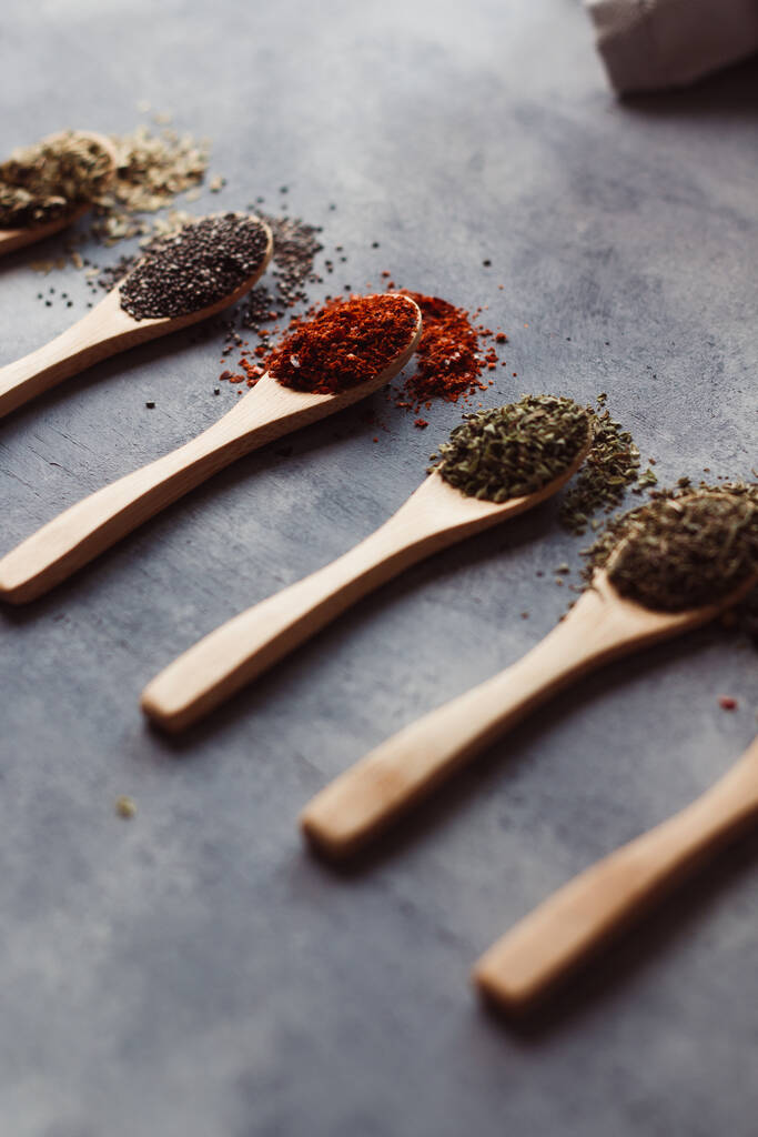 A vertical shot of assortment of spices: chia, paprika, parsley, rosemary, and tea - Photo, Image