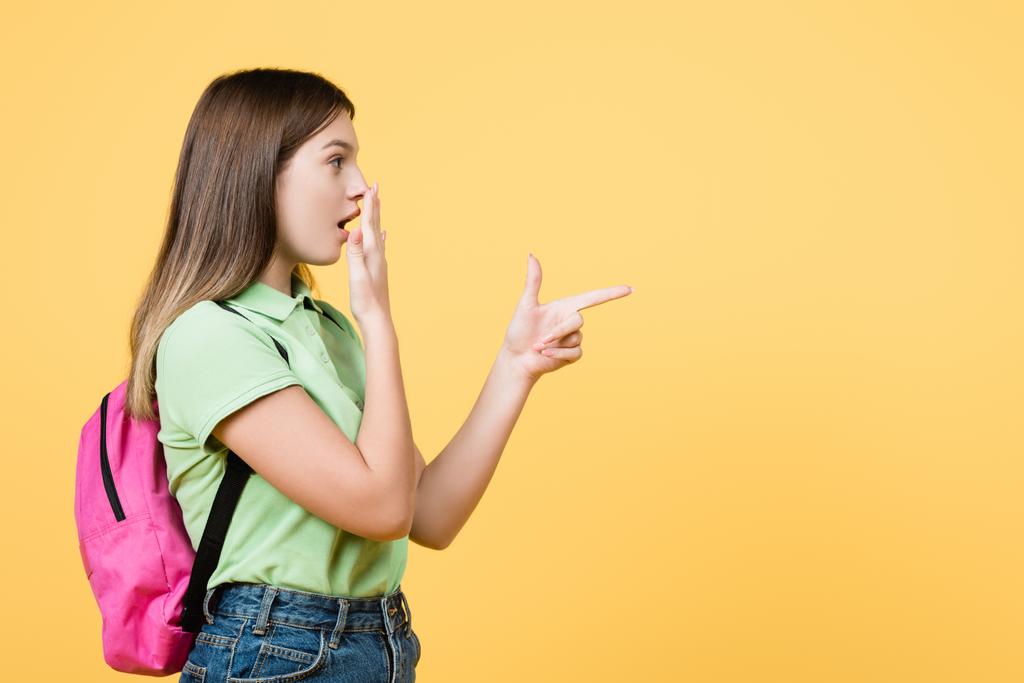 Menina adolescente animado com mochila apontando com o dedo isolado no amarelo - Foto, Imagem