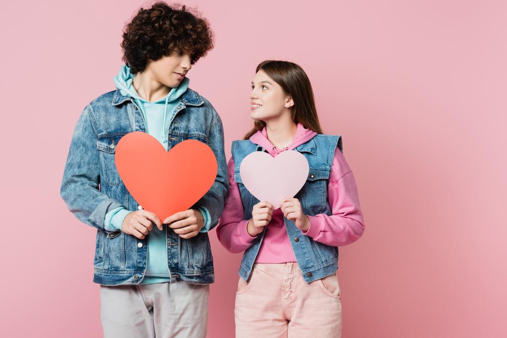 Молодая пара держит бумажные сердца изолированы на розовый - Фото, изображение