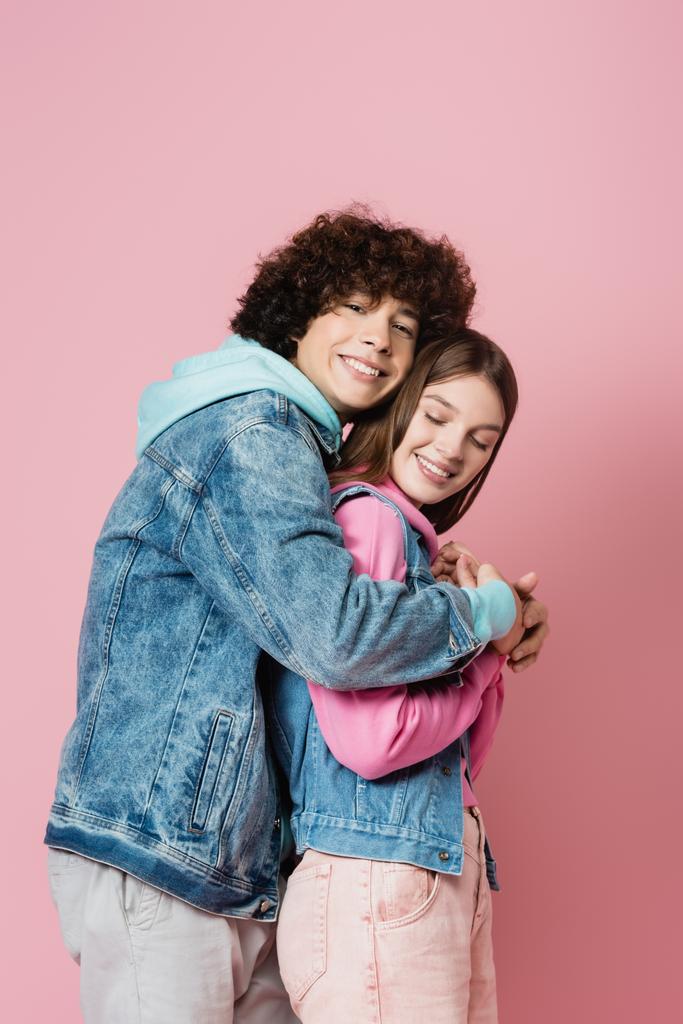 Widok z boku kręcone nastolatek obejmujący dziewczyna na różowym tle  - Zdjęcie, obraz