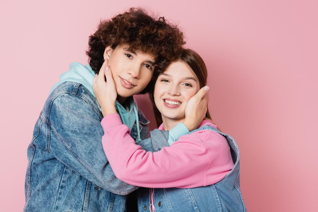 Feliz adolescente pareja abrazando en rosa fondo - Foto, Imagen