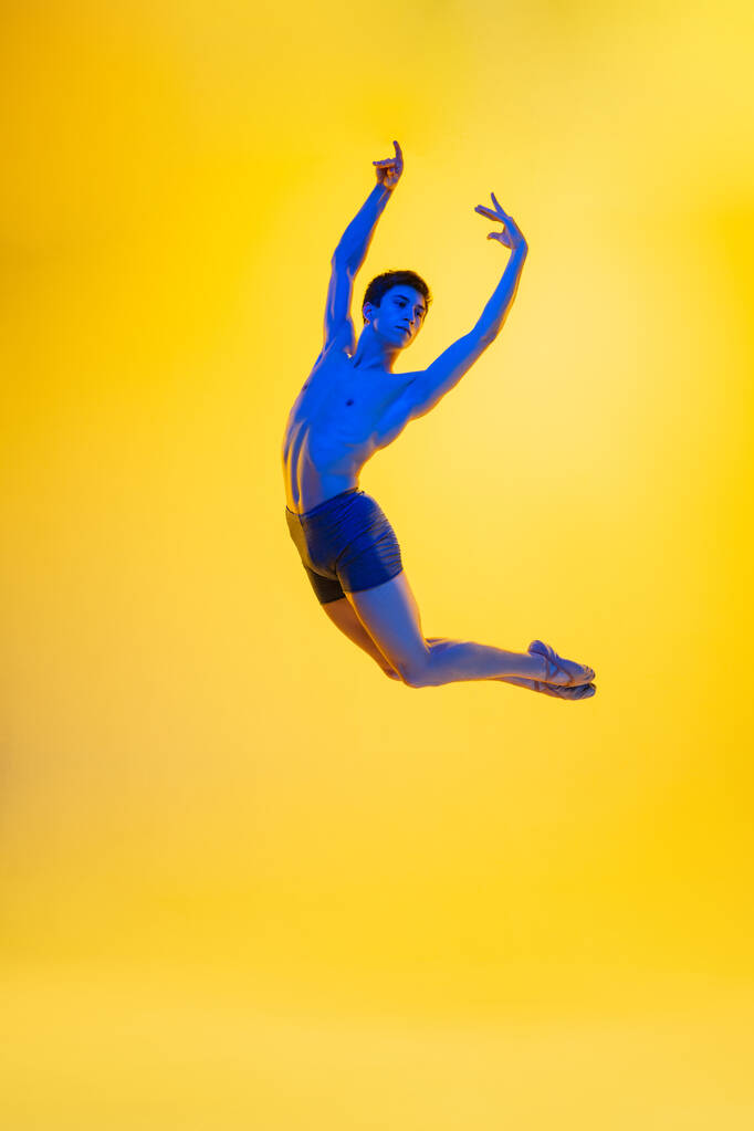 Jeune et gracieuse danseuse de ballet isolée sur fond de studio jaune au néon. Art, mouvement, action, flexibilité, concept d'inspiration. - Photo, image