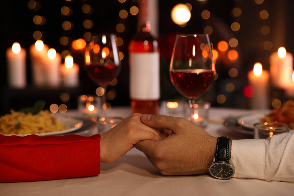 Lokantada romantik bir akşam yemeğinde el ele tutuşan çift, yakın plan. - Fotoğraf, Görsel