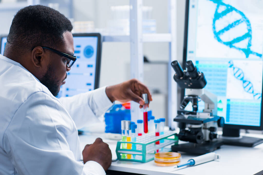 Científico profesional afroamericano está trabajando en una vacuna en un moderno laboratorio de investigación científica. Trabajo de ingeniero genético. Tecnología y ciencia del futuro. - Foto, imagen