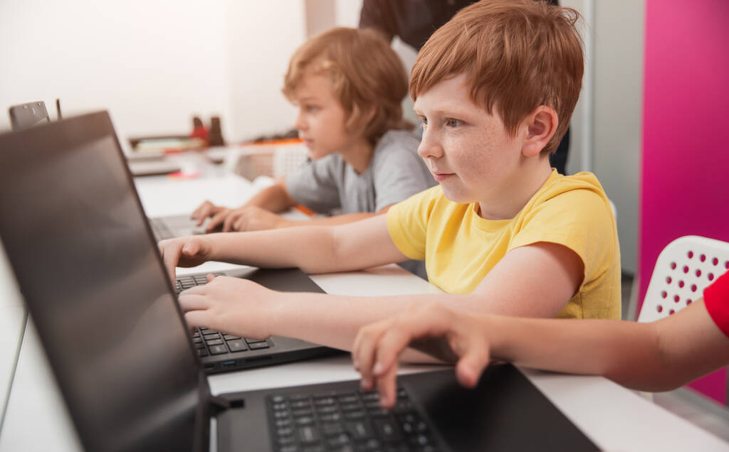 Skupiony uczeń pracujący na laptopie podczas lekcji szkolnej - Zdjęcie, obraz