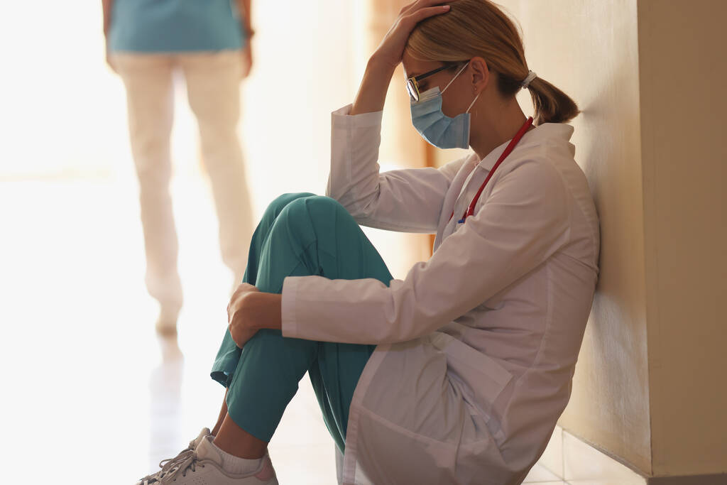 Frusztrált orvos ül a kórház folyosóján közelkép - Fotó, kép