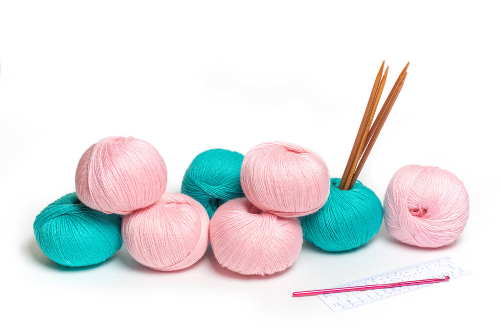 Las madejas rosadas y verdes del hilo de lana. Tejido a mano y herramientas para ello - Foto, imagen
