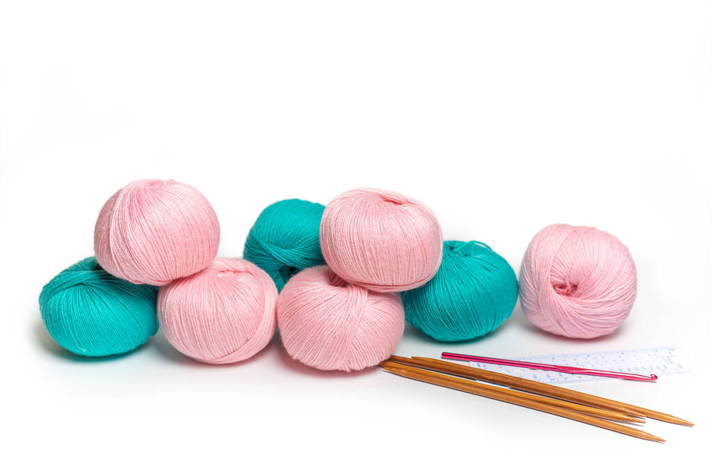 Las madejas rosadas y verdes del hilo de lana. Tejido a mano y herramientas para ello - Foto, imagen