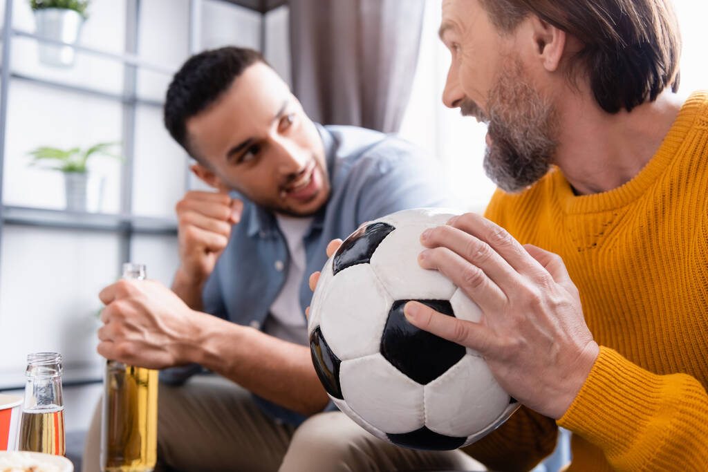 młody Hiszpan pokazując gest wygranej podczas oglądania meczu piłki nożnej z tatą w domu, zamazane tło - Zdjęcie, obraz
