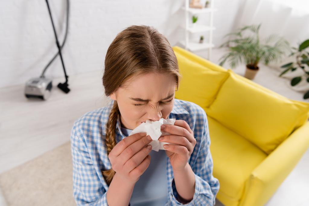Вид сверху на женщину, страдающую аллергией возле пылесоса в гостиной на размытом фоне  - Фото, изображение