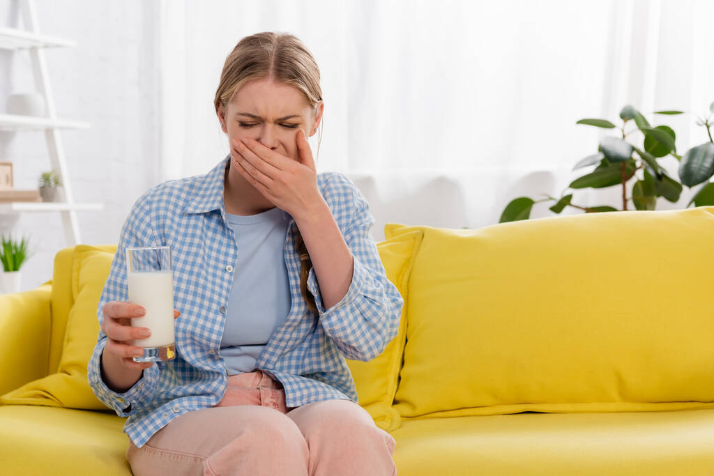 Mulher com alergia sentindo nojo enquanto segura um copo de leite  - Foto, Imagem