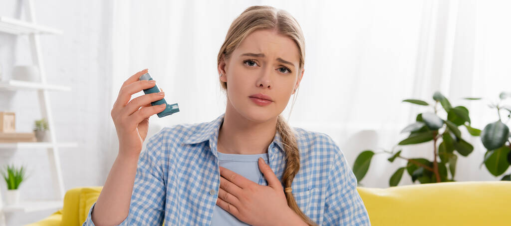Sad woman holding inhaler at home, banner  - 写真・画像