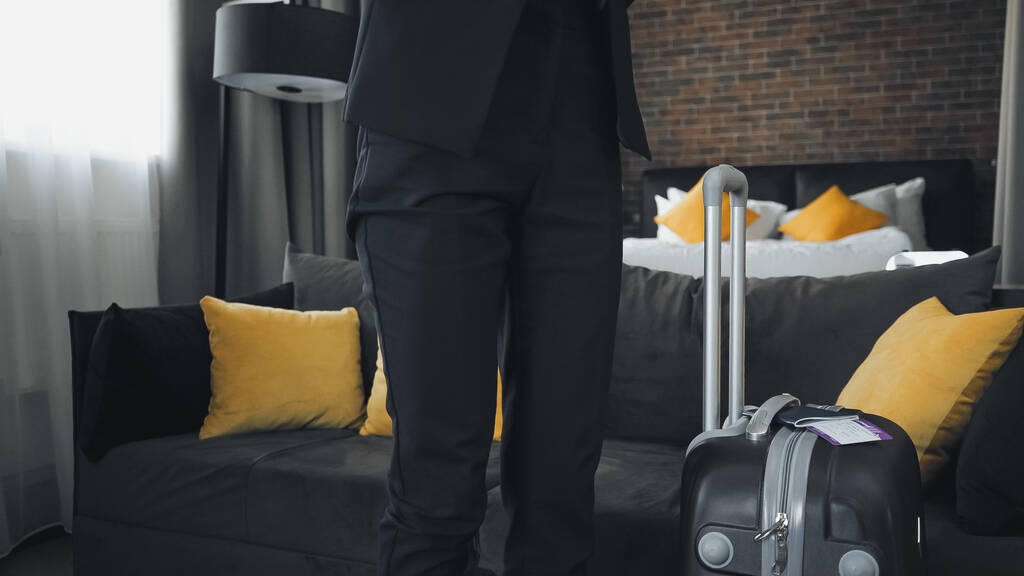 обрізаний вид бізнес-леді, що стоїть біля валізи
 - Фото, зображення