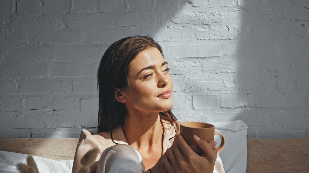 szczęśliwa kobieta trzyma filiżankę herbaty i odwraca wzrok - Zdjęcie, obraz
