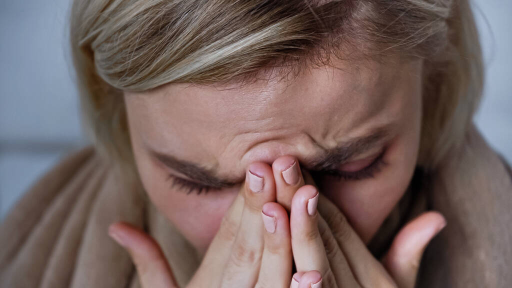 крупным планом видно, как больная женщина чихает и закрывает нос руками - Фото, изображение