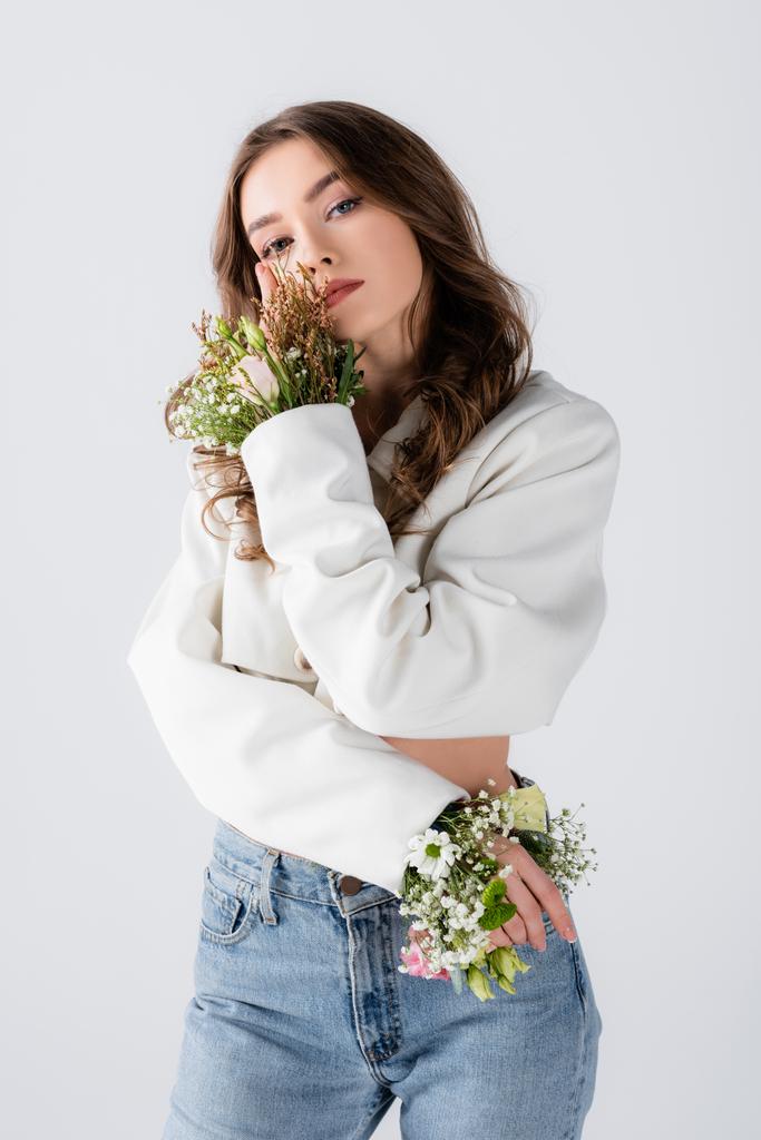 Jonge model met bloemen in mouwen van jas poseren geïsoleerd op grijs  - Foto, afbeelding