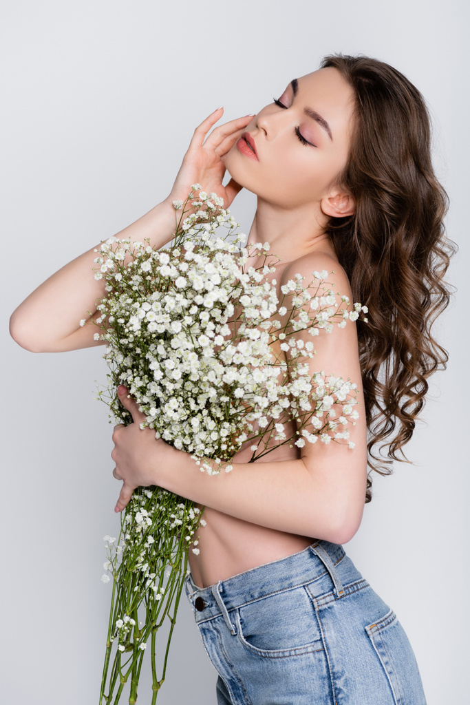 Shirtless brunette vrouw poseren met bloemen geïsoleerd op grijs  - Foto, afbeelding
