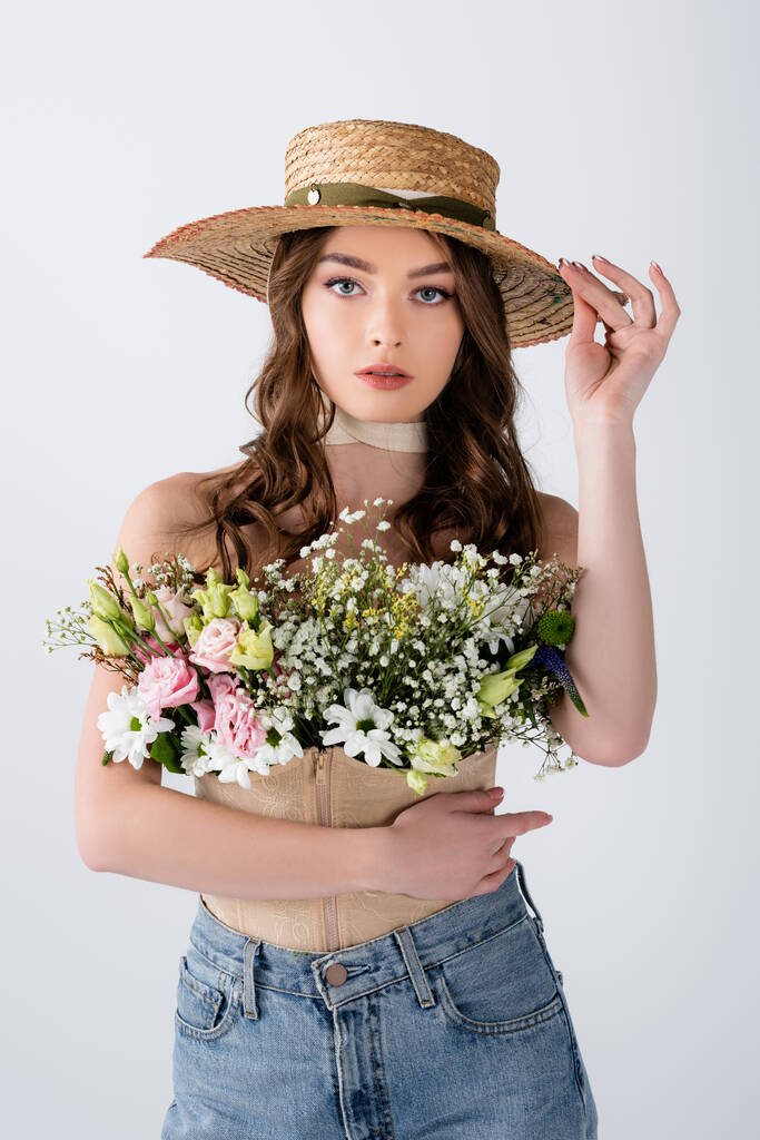 Modèle Brunette tenant chapeau de soleil et fleurs en chemisier isolé sur gris  - Photo, image