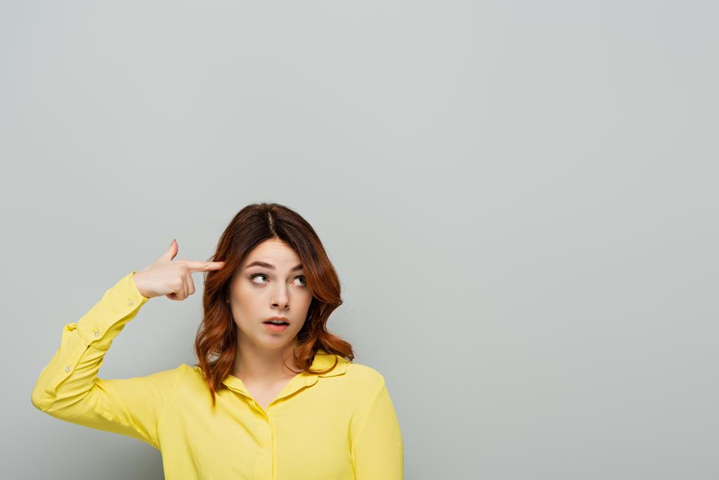 mujer disgustada mostrando gesto estúpido mientras mira hacia otro lado en gris - Foto, Imagen