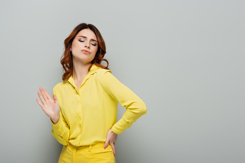 smug woman showing refuse gesture while standing with hand on hip on grey - Photo, Image
