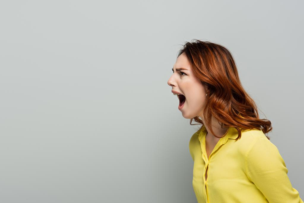 сердита жінка в жовтому короткому крику, дивлячись на сіру
 - Фото, зображення