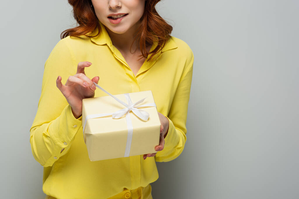 Gri üzerinde hediye kutusu açan cilveli kadının kısmi görüntüsü - Fotoğraf, Görsel
