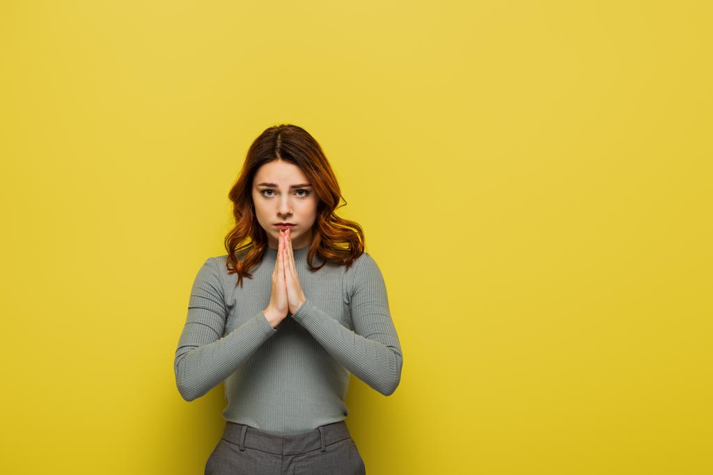 preoccupato donna mostrando si prega di gesto mentre guardando la fotocamera sul giallo - Foto, immagini