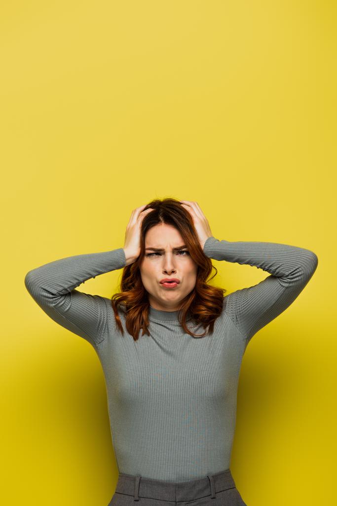 mulher estressada tocando a cabeça enquanto sofre de dor de cabeça no amarelo - Foto, Imagem