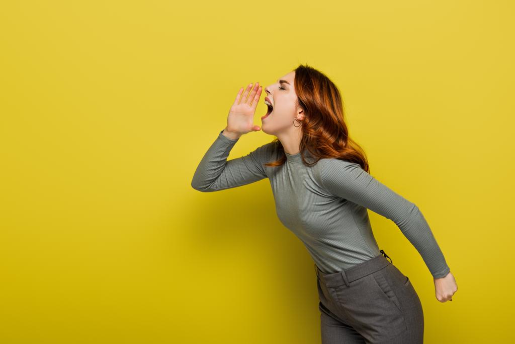 mujer joven con el pelo ondulado gritando en amarillo - Foto, imagen