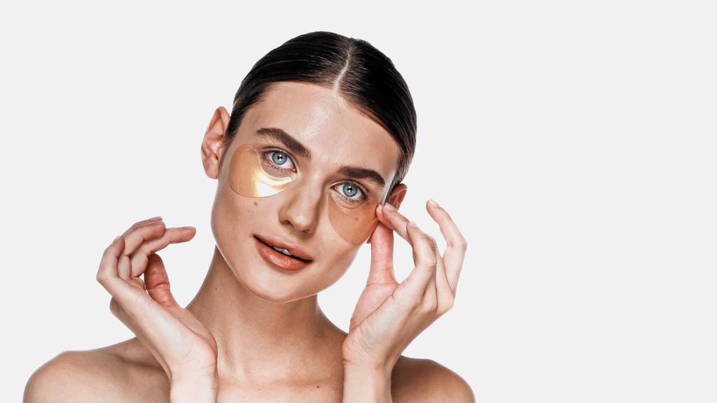 Frau appliziert Augenklappen unter Augen isoliert auf weiß - Foto, Bild