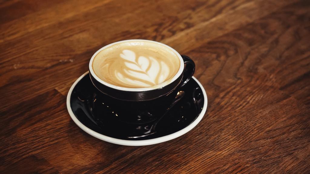 Tasse leckeren Cappuccino mit Latte Art auf dem Tisch - Foto, Bild